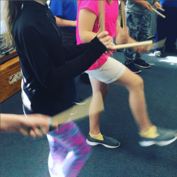 Picture of students dancing and playing rhythm sticks.