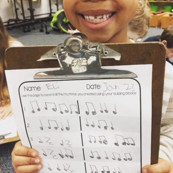 Child holding worksheet with musical notes on the front.