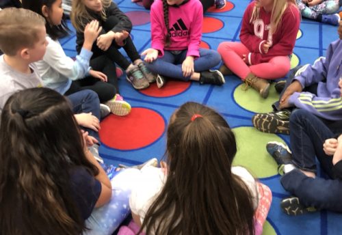 Children sitting in circle for centers activity.