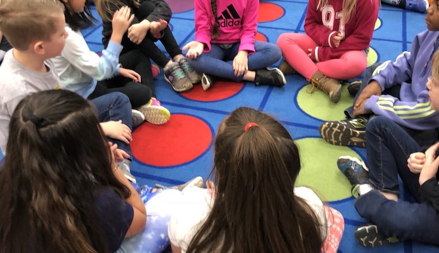 Children sitting in circle for centers activity.